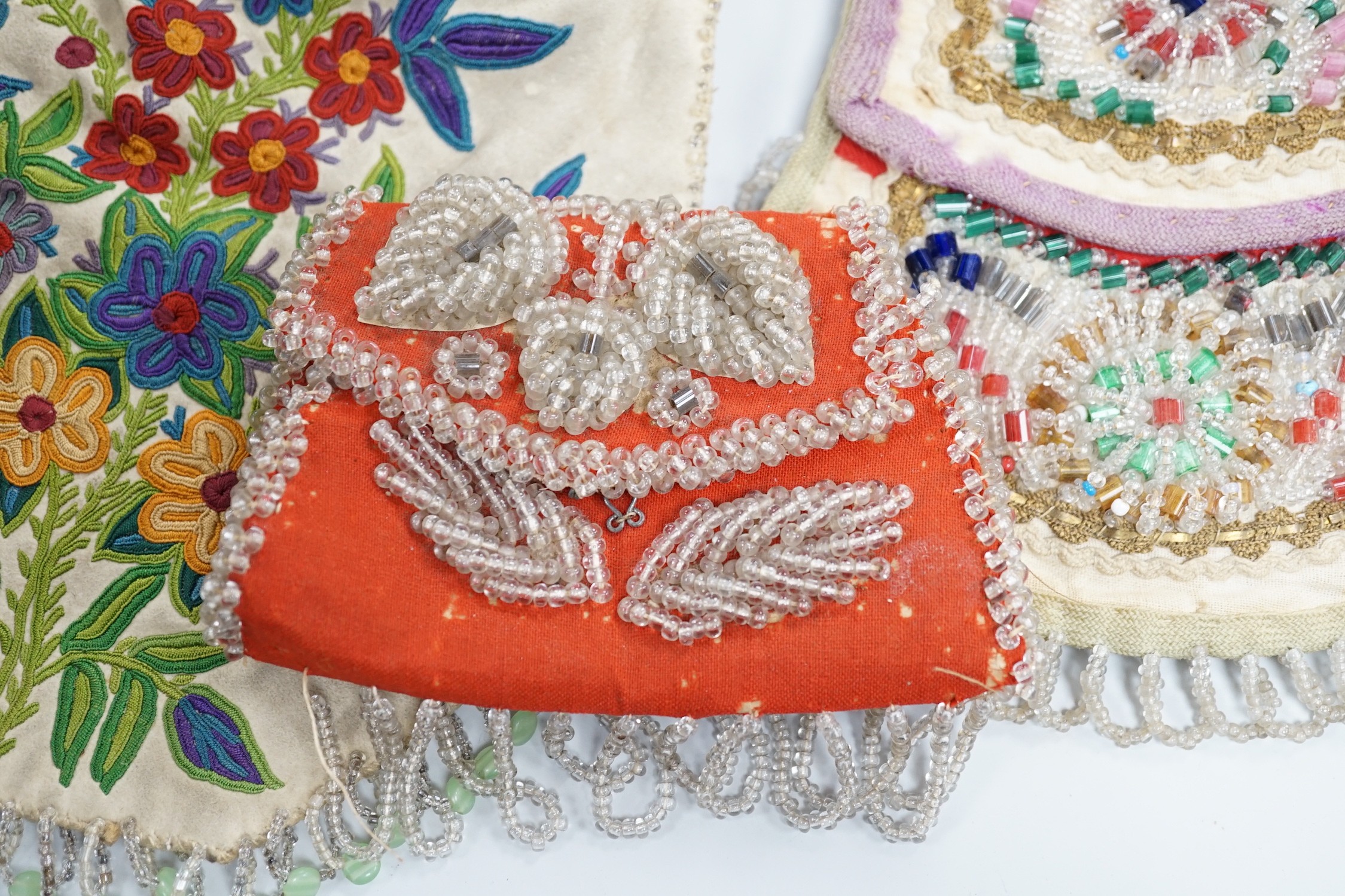A mid to late 19th century Iroquois, North American/Canadian Indian glass beadwork bag on linen, together with a smaller red wool beaded purse and a 20th century suede embroidered bag with beaded fringe